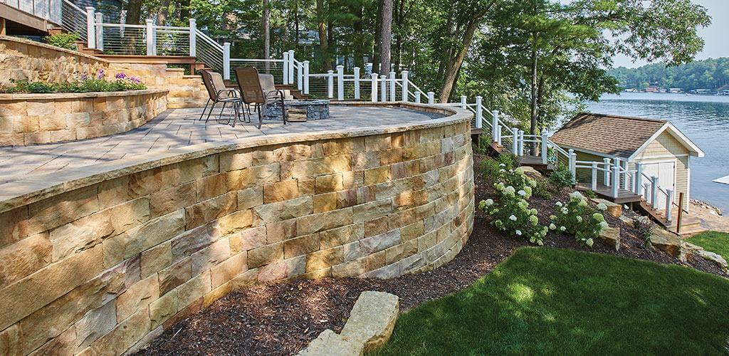 A beautiful elevated patio sits atop a curved wall made of Harvest Gold Sandstone Sawn Cut Drywall .