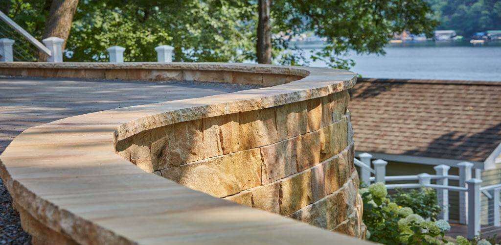 A beautiful stone retaining wall curves around an elevated patio.