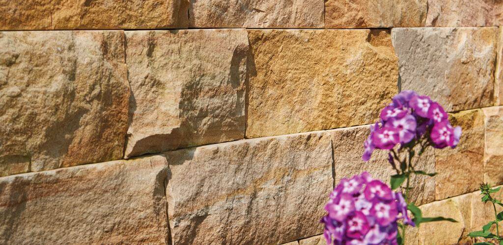 The texture of a beautiful stone retaining wall is accentuated by golden sunlight.