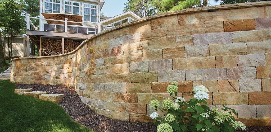 A beautiful curved stone retaining wall separates two levels of a backyard.