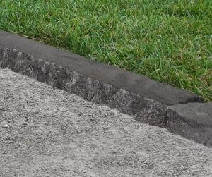 Dark edging stone borders green grass and a pathway.