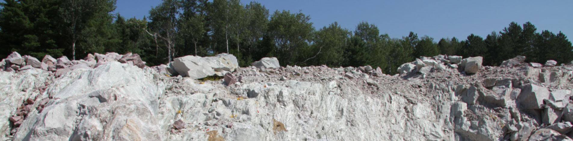 A quarry is shown with sloping, jagged edges and large stone boulders scattered around.