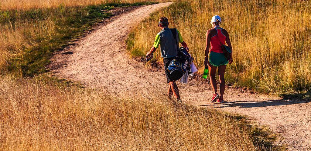 Two golfers are shown walking on a pathway made of Kafka Stabilized Pathway Mix.