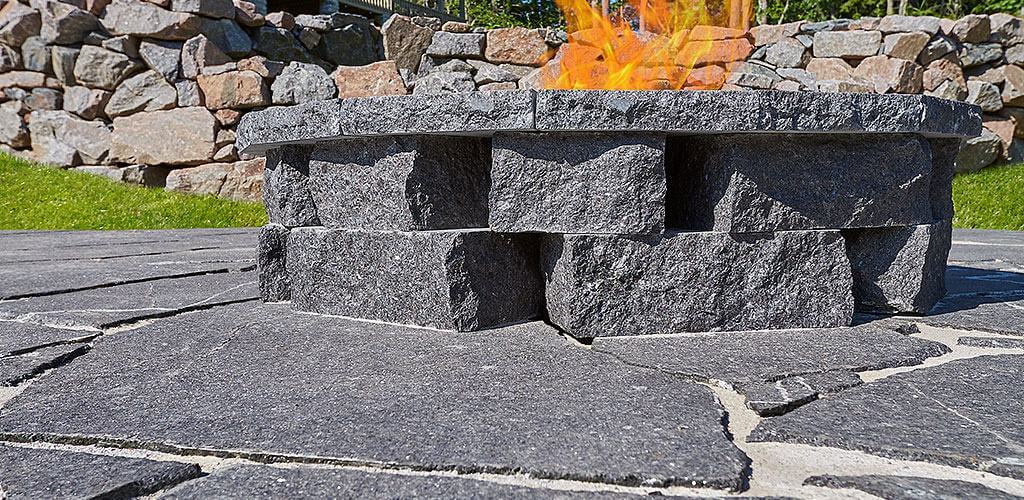 A beautiful fire pit is shown in Starlight Black Granite irregular thermal flagstone.