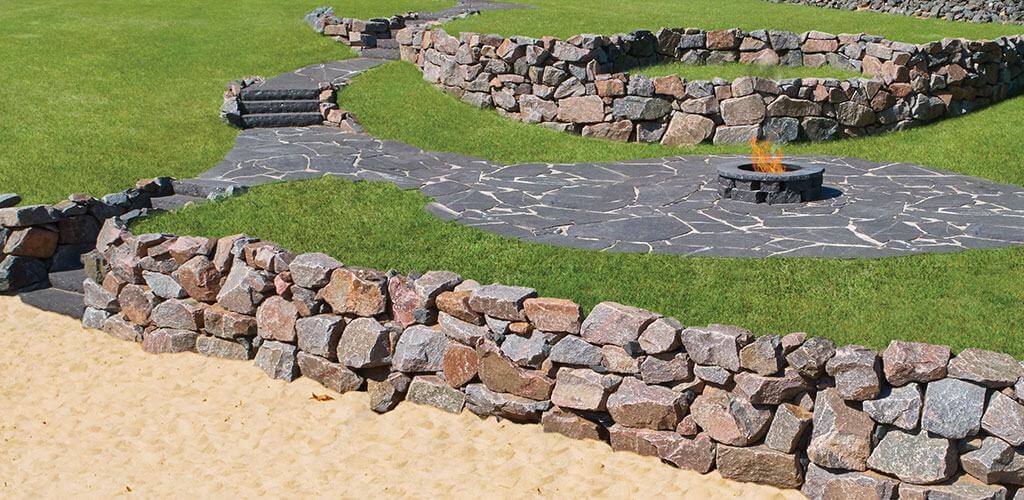 A Starlight Black Granite Irregular Thermal Flagstone pathway is shown meandering between several stone retaining walls.