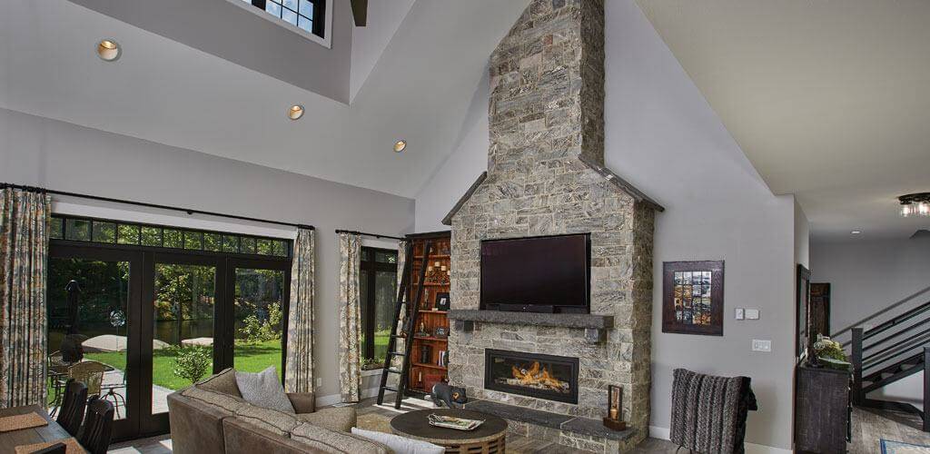 A beautiful stone veneer fireplace extends up into the vaulted ceiling of a beautiful living room.