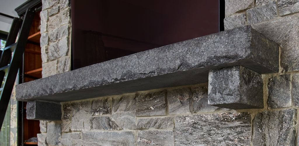 A Starlight Black Granite mantel is shown above a beautiful fireplace.