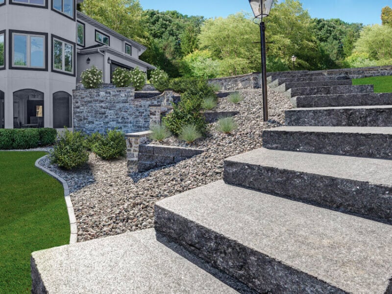 Large stone steps curl down a decline from a driveway to the backyard.